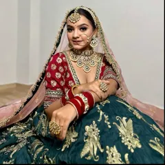 A stunning combination of a deep green lehenga with gold embroidery and a contrasting red blouse. This look is both royal and unique.