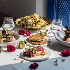 Sunlight streams over a table laden with our innovative Indian dishes, highlighting the fresh ingredients and beautiful colors of our food.