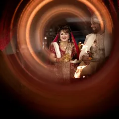 A creative and joyful shot of the couple during a wedding ritual, captured through a ring of fire or light painting for an artistic effect.
