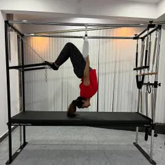An inverted hanging exercise using the fuzzy straps on the Cadillac, which is excellent for spinal decompression and strengthening the entire posterior chain.