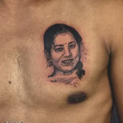A finished portrait tattoo on the chest. The soft shading and precise details in the face create a realistic and moving tribute to a loved one.