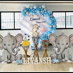 Liyansh's first birthday also featured the popular baby elephant theme. This setup includes two large elephant props, a striped blue and white backdrop, and star-shaped marquee lights for a touch of sparkle.