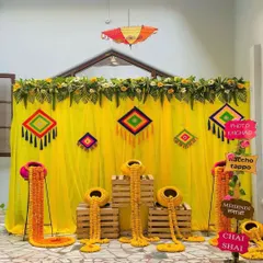This quirky and colorful mehendi backdrop is full of fun details. I used a bright yellow curtain with Rajasthani-style hangings, marigold arrangements in traditional pots, and playful signs like 'Photo Khichao' to encourage guest interaction.