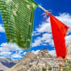 A view of the iconic Key Monastery in Spiti Valley, framed by colorful Buddhist prayer flags. The flags carry prayers on the wind, adding to the spiritual atmosphere of the place.