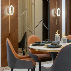 A close-up of a dining nook where we combined textures and lighting to create an intimate setting. The wall features a mix of diagonal wood paneling and custom-cut mirrors, accented by modern oval wall sconces that cast a warm glow on the space.