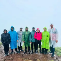 A group of trekkers in raincoats on the foggy Tadiandamol trail. The monsoon adds a special magic to the Coorg landscape.