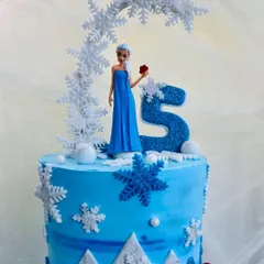A close-up of my Elsa-themed cake, showing the detailed snowflake arch and the glitter on the number five. Every element is carefully crafted to capture the magic of the Frozen world.