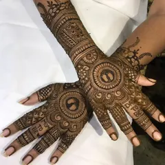 A special mehendi design for a baby shower, featuring tiny baby feet inside a circle and the words 'Mom to be' and 'Dad to be' on the fingers.