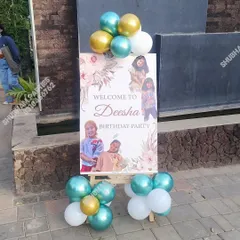A personalized welcome board on an easel for a birthday party, decorated with balloons.