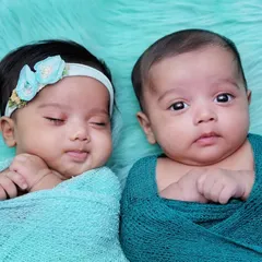 A beautiful portrait of newborn twins, one sleeping and one awake. This shot perfectly captures a real, unscripted moment between them.