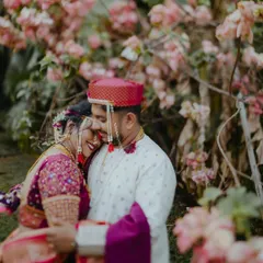 A tender moment between a Maharashtrian couple in their wedding attire, surrounded by blooming flowers. This portrait showcases their connection and the beauty of their traditional outfits.