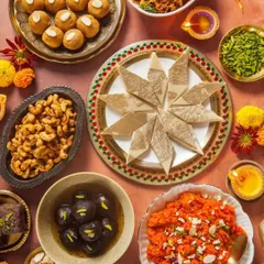 A beautiful flat lay of my Diwali sweets collection, including Kaju Katli, Gulab Jamun, Gajar Halwa, and Laddoos, surrounded by diyas and festive decor.