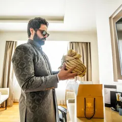 A quiet moment of preparation for the groom. Holding his safa (turban), he gets ready for the most important day, a candid shot filled with anticipation.