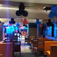 The full view of an Avengers-themed birthday party venue. We decorated the entire space with hanging balloon bunches in red, blue, and black to match the main stage setup.