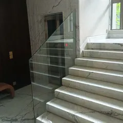 A frameless glass railing for a marble staircase. This minimalist design provides safety without obstructing the view, making the space feel larger and more open.