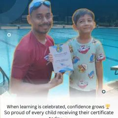 A young swimmer proudly receives his certificate from his coach. Celebrating these milestones is key to building a child's belief in themselves.