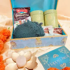 This elegant blue printed trunk box is a gift in itself. Inside, it holds ceramic jars of goodies, coasters, and delicious wafers, making for a beautiful and useful Diwali present.