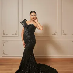 The Fantasia gown is pure drama. This black sequined mermaid dress features a unique, structured shoulder detail and a long trail.