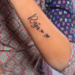 This "Raja" name tattoo is combined with a small heart and birds in flight. Adding small symbols like these is a great way to personalize a name tattoo.