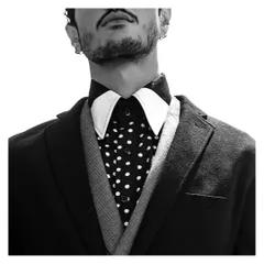 A detail shot focusing on the art of layering in menswear. This look combines a polka-dot shirt with a uniquely styled double collar and a structured blazer, showcasing attention to detail in high-fashion styling.