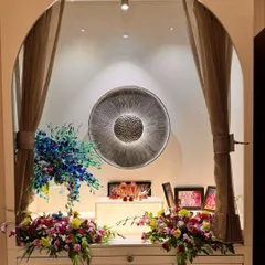 A tranquil prayer and devotion nook designed within a living area. The space is framed by a simple arch and soft curtains, with a hammered metal art piece serving as a spiritual focal point. It’s a perfect example of integrating sacred spaces into daily life.
