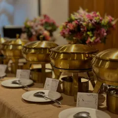 A close-up of our classic brass buffet setup. Each dish is neatly labelled, with clean plates and cutlery ready for guests. This is how your party will look when we cater it.