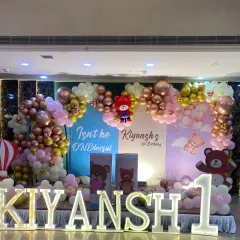 For a child's first birthday, I can create a magical world. This "ONEderful" teddy bear theme includes a full stage setup with custom backdrops, a multi-colored balloon arch with rose gold and chrome accents, and large marquee letters spelling out the birthday boy's name.