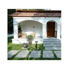 A closer look at the veranda design, where comfort is key. The space is designed to be a cozy nook for reading or conversation, protected from the elements while still feeling open to the garden. The patterned floor tiles and simple, comfortable seating complete this inviting outdoor room.