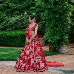 A quiet moment of reflection before the ceremony. This full-length view showcases the magnificent flare and detailed craftsmanship of her traditional red bridal lehenga.