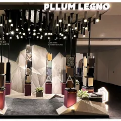 A closer look at the Pllum Legno installation, where veneer samples are presented on totems. The dramatic overhead lighting, resembling a shower of light, turns the entire space into a theatrical display.