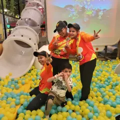 A child and our friendly staff members pose for a fun photo in the middle of the ball pit.