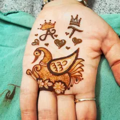 This design is full of personal symbols. It features the couple's initials 'A' and 'T' with crowns, hearts, and a beautifully detailed swan, telling a small story on the palm.