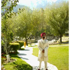 The groom, Rishi, standing in the lush gardens of the Manali wedding venue. The snow-capped mountains in the background add a majestic touch to this outdoor groom portrait.