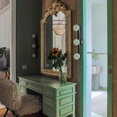 The master suite in Summer Haus includes this elegant vanity area. The design combines a vintage-inspired mirror with modern lighting and a custom desk, leading into a spacious walk-in closet.