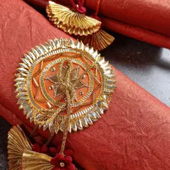 A close-up of our handmade wedding scrolls. This one features a beautiful orange fabric with a traditional gota-patti style emblem, perfect for a royal-themed wedding.