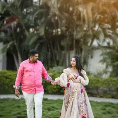 A candid moment during an outdoor couple's shoot. The partners hold hands and walk through the grass, sharing a smile and enjoying the beautiful natural surroundings.