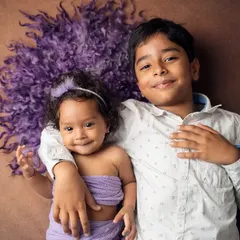 An adorable overhead shot of a brother and sister. We use creative angles and cozy props to create unique and heartwarming sibling portraits that show their special bond.