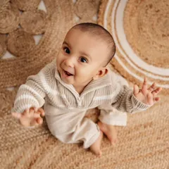 A happy baby portrait from a high angle, showing off his sweet smile and our cozy jute rug.