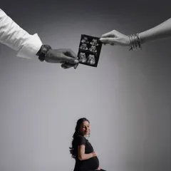 A creative and artistic composition. The parents' hands hold the sonogram above the mother-to-be, symbolizing their joint love and protection over their growing family.