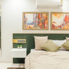 A different angle of the bedroom, showing the balance between the green headboard and the warm-toned artwork above. The layered lighting, including bedside lamps and ceiling lights, allows for adjustable ambiance.