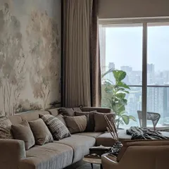 This living space, featuring a large sectional sofa, is perfectly anchored by a serene landscape mural. The wallpaper adds a layer of artistry and nature, creating a harmonious and inviting atmosphere for relaxation.