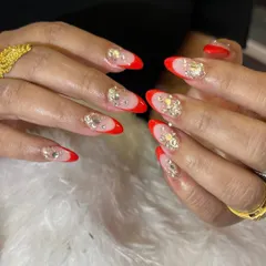 A bold and glamorous design with a bright red French tip and accent nails covered in chunky, iridescent rhinestones.