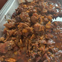 A tray of my rich, slow cooked pulled pork, ready to be served. It’s coated in its own flavourful tomato and BBQ reduction, perfect for filling burgers or baos.
