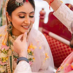 A sacred moment as sindoor is applied. The bride's serene expression and the soft, glowing makeup create a picture of timeless tradition and beauty.