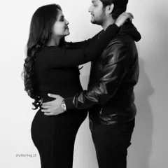 A modern black and white portrait of an expecting couple. Their coordinated casual outfits and loving gaze create a stylish and intimate photograph that feels authentic and timeless.