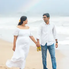 A walk on the beach becomes an announcement, with the couple holding a tiny pair of yellow baby shoes, a symbol of the new life they're waiting for.