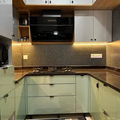 A close-up of the cooking area, featuring a sleek black chimney and hob. The under-cabinet lighting not only illuminates the workspace but also highlights the beautiful texture of the backsplash tiles.
