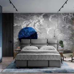 Inspired by a nautical escape, this bedroom features a dramatic cloud-mural wallpaper. The deep blue circular art piece and grey upholstered bed create a serene, dreamy atmosphere reminiscent of the sea.