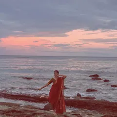 An aquatic stage. Performing a dance pose in a saree against a beautiful sunset over the ocean on Reunion Island.