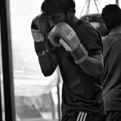 A fighter practices keeping his guard tight while throwing combinations on the heavy bag. This drill builds muscle memory for defense.